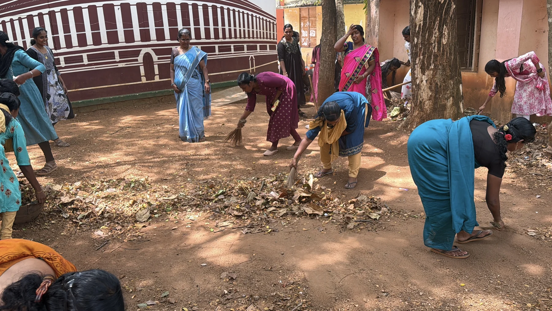 Participants sweeping and collecting leaves in the school grounds